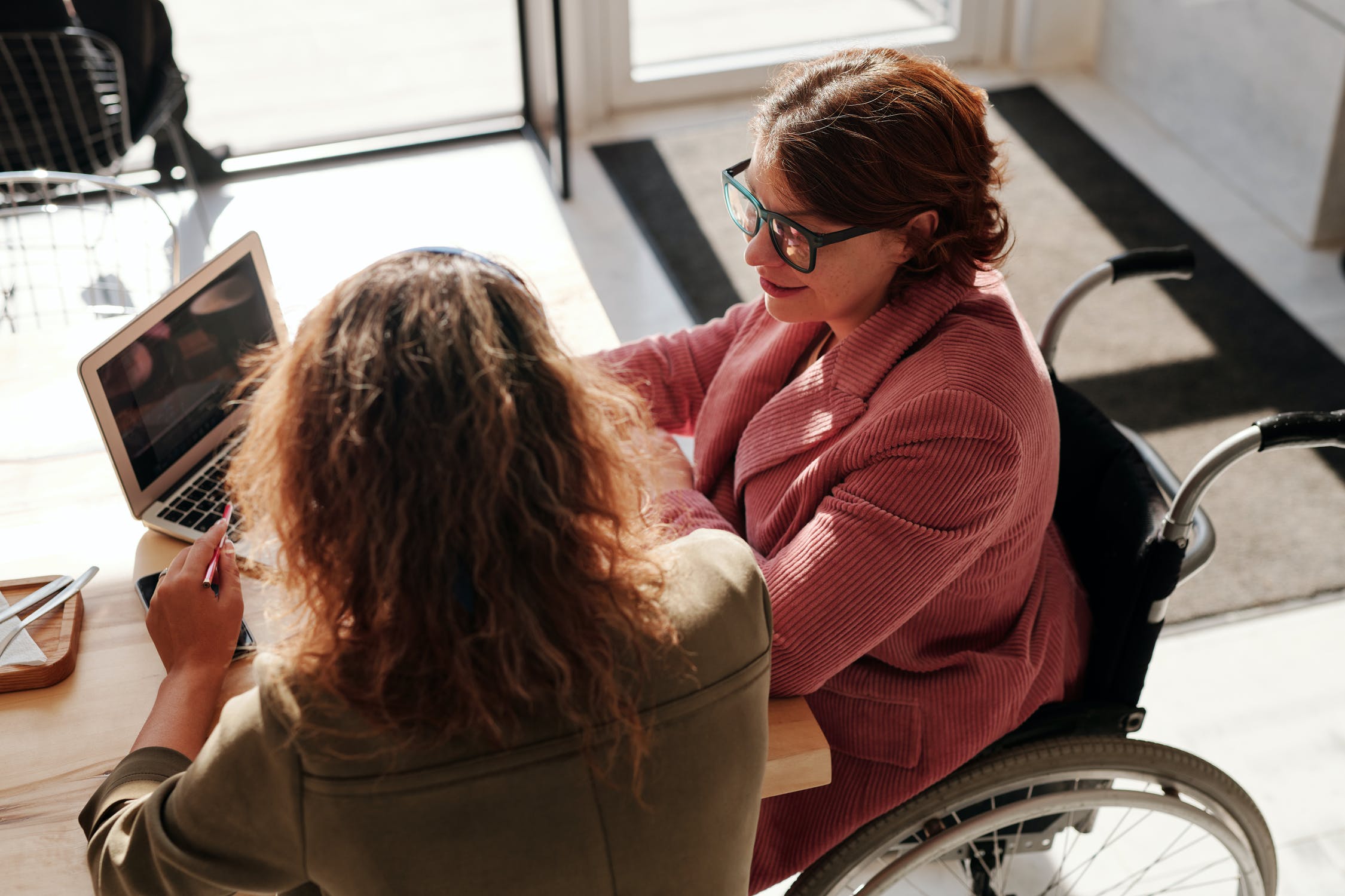 A wheelchair user sits with someone discussing rehabilitation Physiotherapy